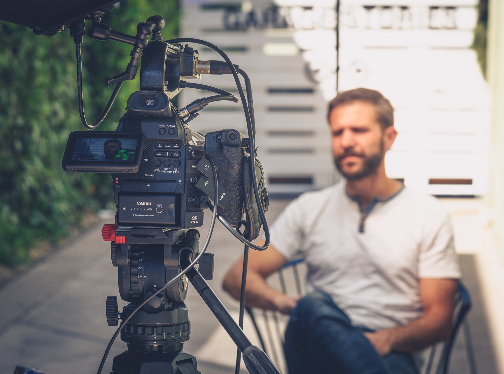 man sitting down in yard and talking to cinema camera